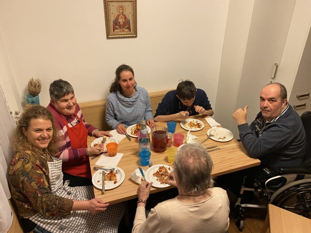 Sechs Menschen sitzen um einen Tisch und genießen ein gemeinsames Essen.
