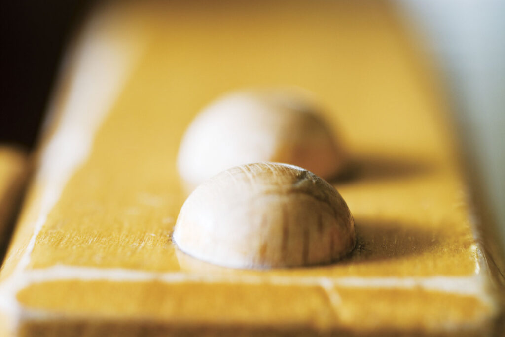Nahaufnahme von zwei halbrunden, hölzernen Noppen auf einer gelben, glatten Oberfläche.