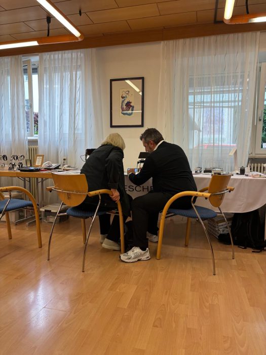 Ein Fachmann erklärt einer Frau die Funktion von Hilfsmitteln. Un esperto spiega la funzione degli ausili a una signora.