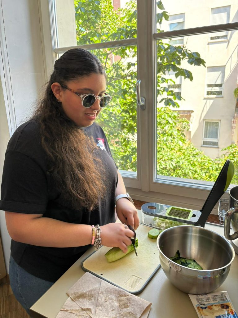 Ein Mädchen lernt, wie man Lebensmittel sicher schneidet. Una ragazza apprende le tecniche per tagliare il cibo in sicurezza.