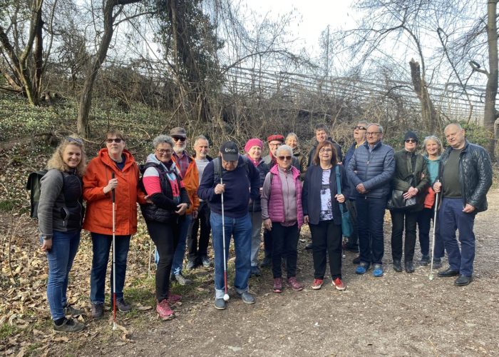 Eine Gruppe von Menschen steht auf einem Waldweg zusammen, einige halten Blindenstöcke.
