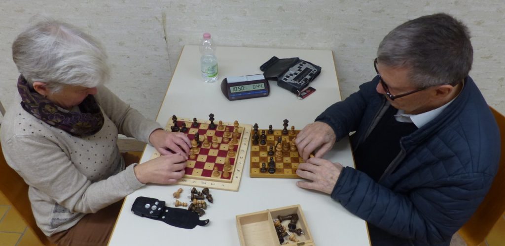 Zwei Personen spielen Schach mit taktilen Figuren auf einem speziellen Brett für Sehbehinderte.