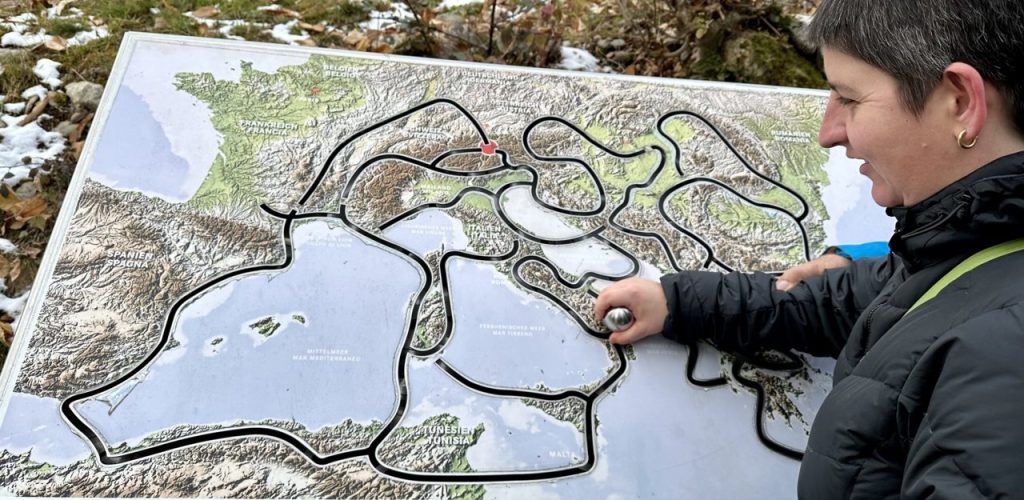 Eine Person tastet eine taktile Europakarte im Freien ab.